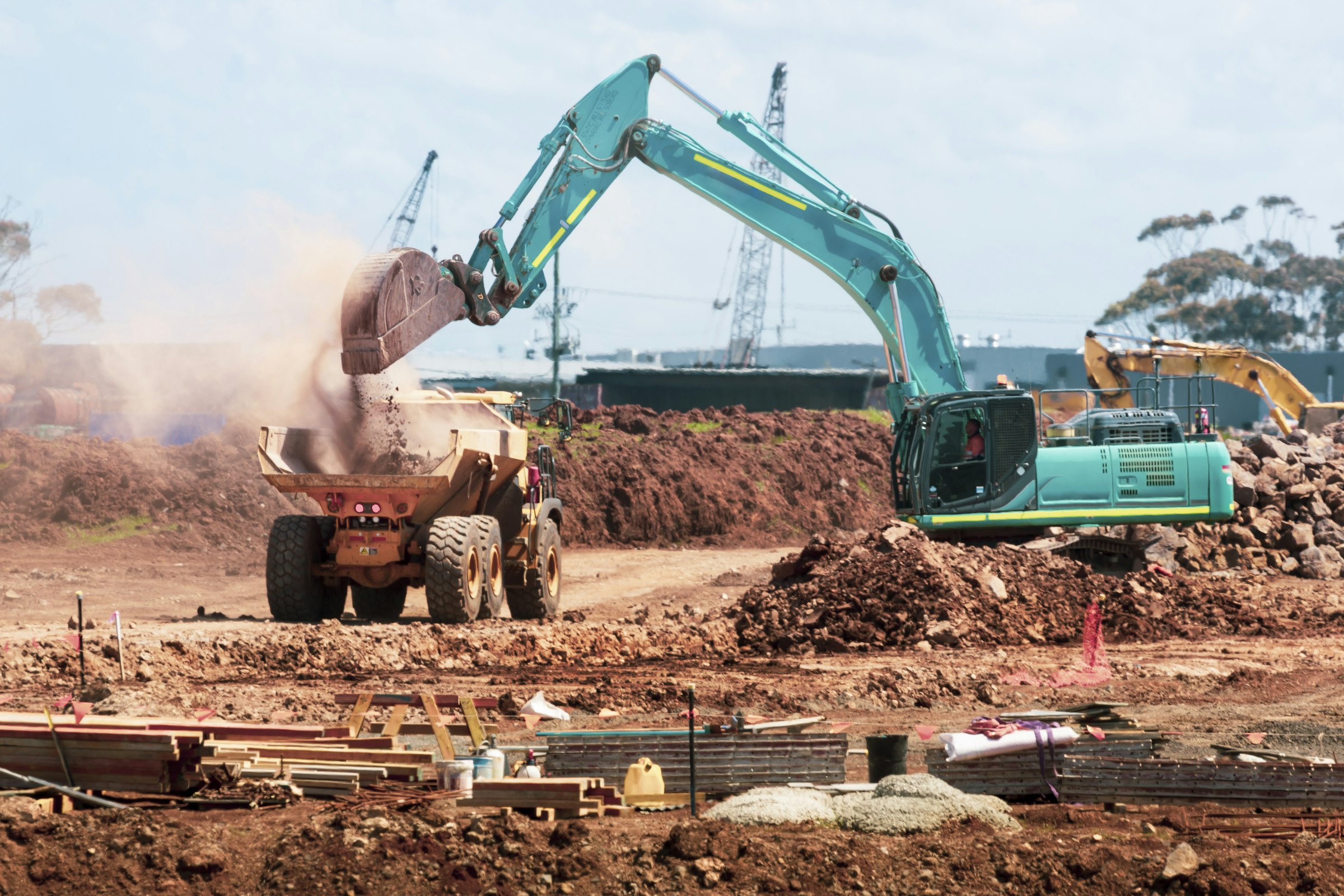 Excavator loading soil into a dump truck on site